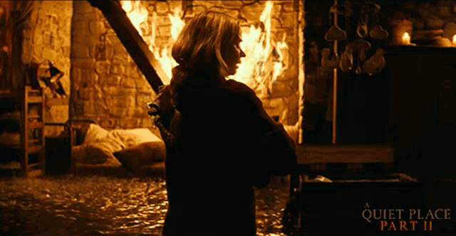 a quiet place part ii poster shows a woman standing in front of a fire