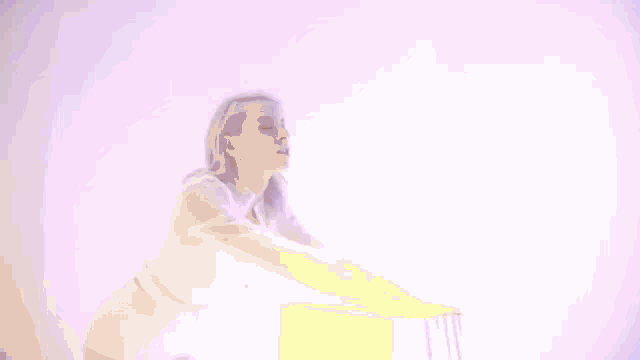 a woman in a white dress is standing in front of a purple wall and a purple light .