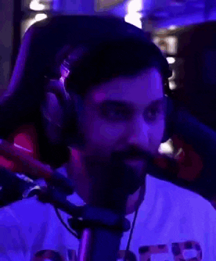 a man with a beard and headphones is sitting in front of a microphone in a dark room .