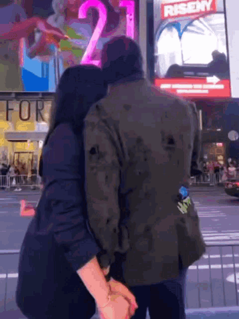 a man and a woman holding hands in front of a riseny sign