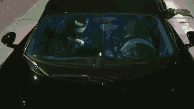 a man is smoking a cigarette while sitting in a car with another man .