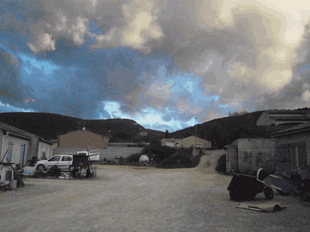 a white truck is parked in a dirt area with a cloudy sky in the background
