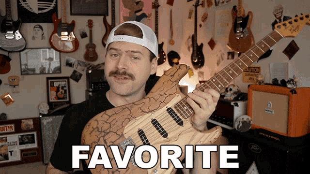 a man holding a guitar in front of a wall that says favorite on it
