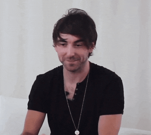 a man wearing a black shirt and a necklace with a circle on it