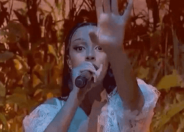 a woman in a white dress is standing in a field of corn and blowing a kiss .