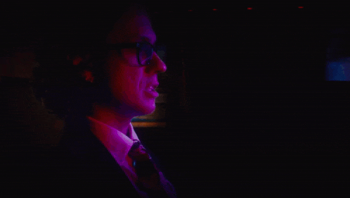 a man in a suit and tie is standing in the dark