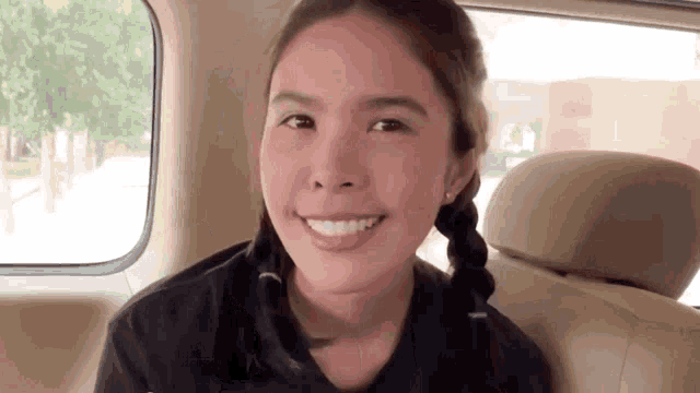 a young woman is sitting in the back seat of a car and smiling .