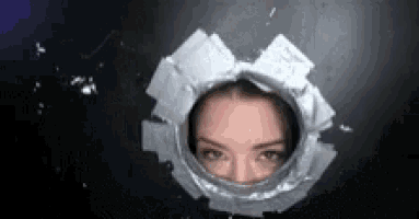 a woman is looking through a hole in a wall .
