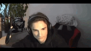 a young man wearing headphones is sitting in front of a microphone in a room .