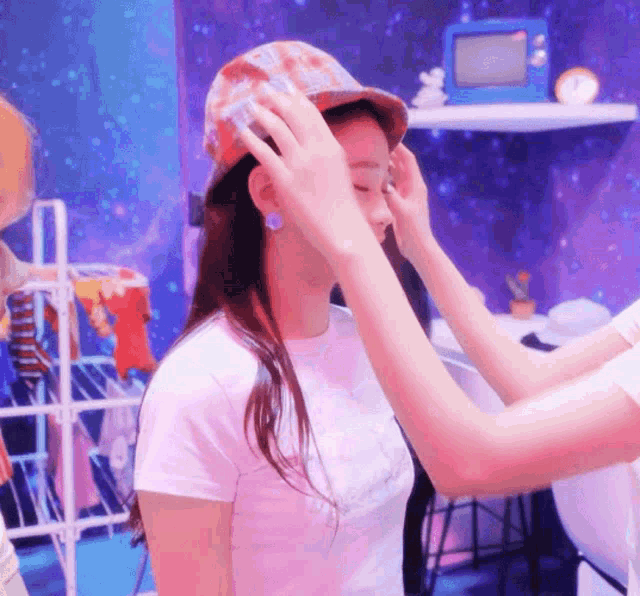 a woman wearing a hat is being helped by another person