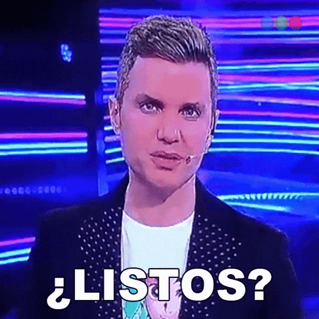 a man is standing in front of a microphone with the words listos written on the screen behind him
