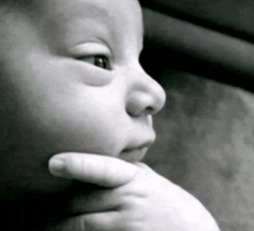 a close up of a baby 's face with a hand on its chin