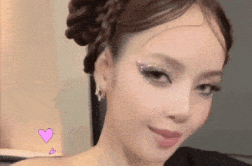 a close up of a woman 's face with a braid in her hair and rhinestones on her eyes .