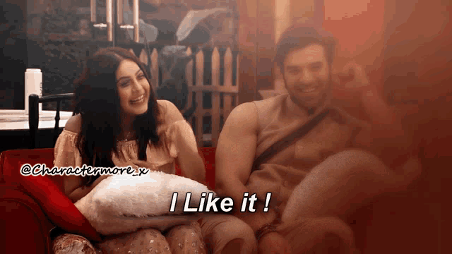 a man and a woman are sitting on a red couch and the man says i like it