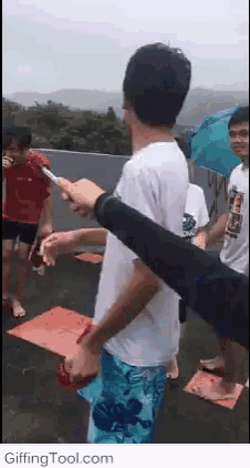 a group of people are standing on a roof with umbrellas and a man is holding a knife .