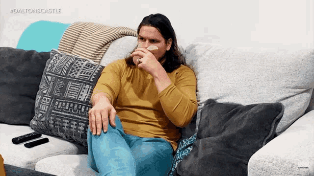 a man is sitting on a couch eating chips with the hashtag dalton iscastle on the bottom right