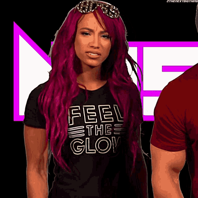 a woman with red hair is wearing a black shirt that says feel the glow