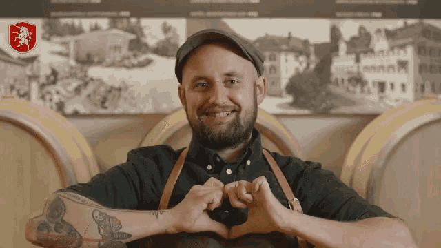 a man making a heart shape with his hands in front of barrels