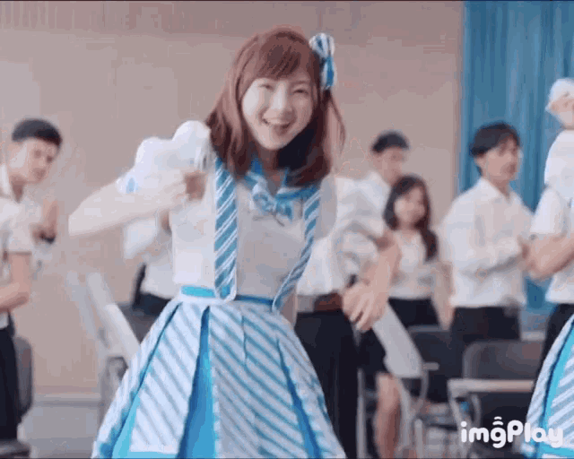 a girl in a blue and white striped dress is dancing in front of a crowd of people .