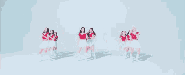 a group of women in red and white dresses are dancing
