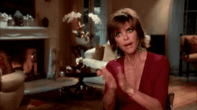 a woman is sitting in a living room clapping her hands .