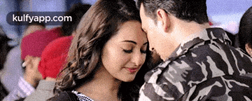 a man and a woman are touching each other 's foreheads in a crowded room .