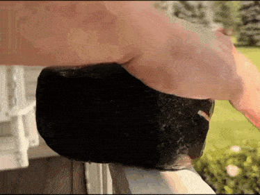 a person is holding a large black rock on a railing outside