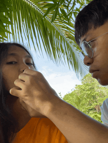 a man touches a woman 's nose under a palm tree leaf