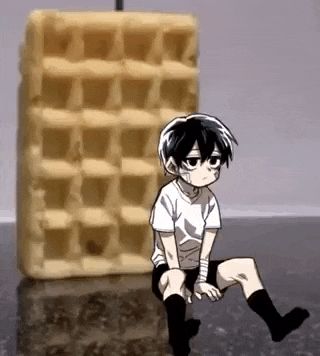 a boy is sitting next to a large waffle on a counter .