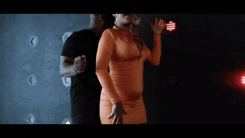 a man and a woman are dancing together and the woman is wearing an orange shirt