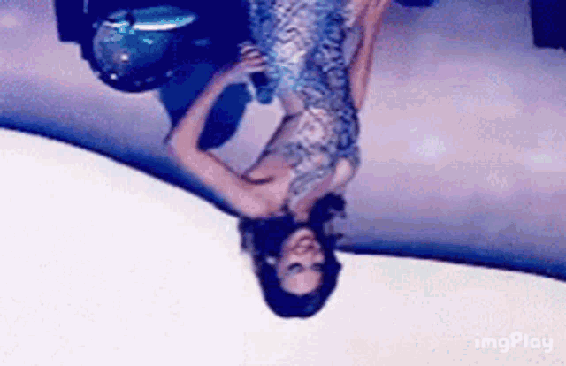 a woman in a dress is standing upside down on a stage .