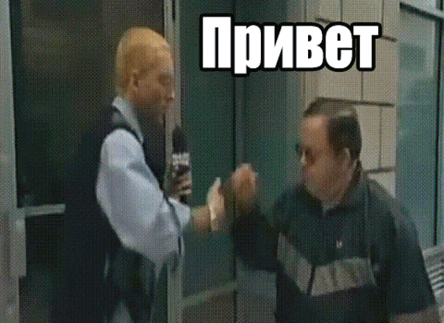 a man is giving another man a high five while holding a microphone in front of him .