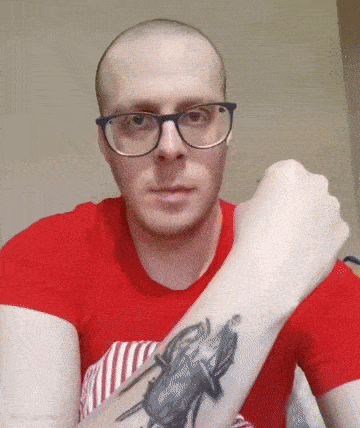 a man wearing glasses has a tattoo on his arm
