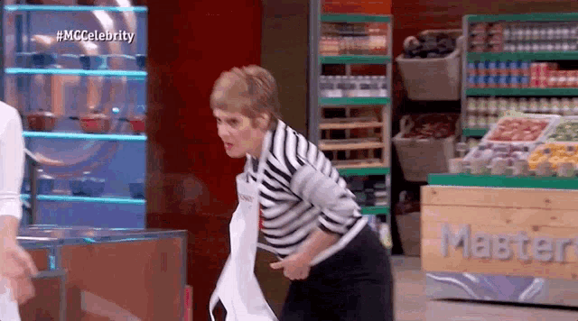 a woman in a striped shirt is standing in front of a counter with the word master on it