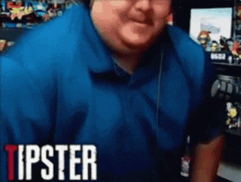 a man wearing headphones and a blue shirt is sitting in front of a television .