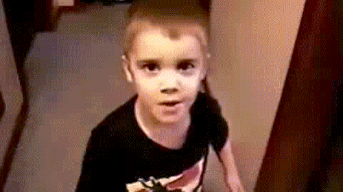 a young boy wearing a black shirt is standing in a hallway .