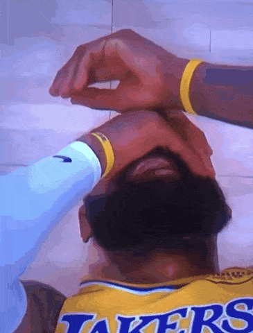 a man wearing a lakers jersey is laying on the floor