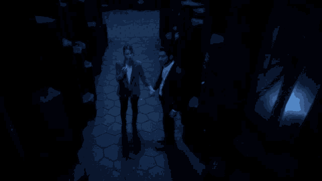 a man and a woman are standing in a dark room holding hands