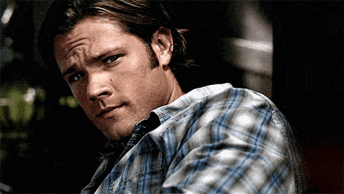 a close up of a man wearing a plaid shirt making a funny face