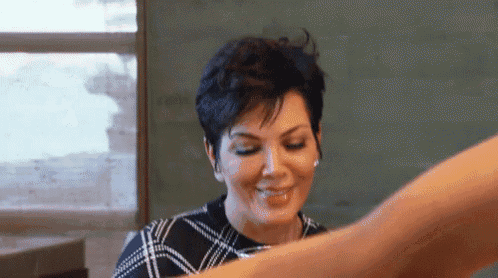 a woman with short hair is sitting at a table with a glass of wine .