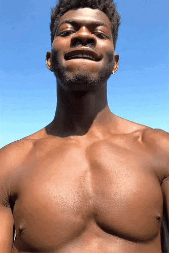 a man without a shirt is smiling and looking up at the camera