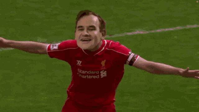 a soccer player wearing a red jersey with the word standard on it is running on the field .