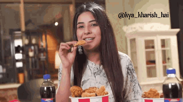 a woman is eating fried chicken and drinking soda