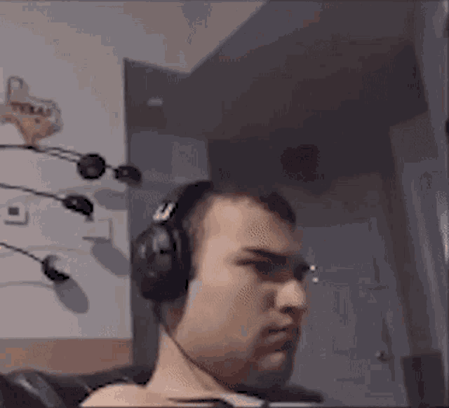 a man wearing headphones is sitting on a couch and making a funny face