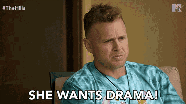 a man in a blue tie dye shirt is sitting in a chair and says she wants drama