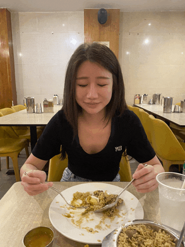 a woman wearing a black shirt with the word wb on it is eating food