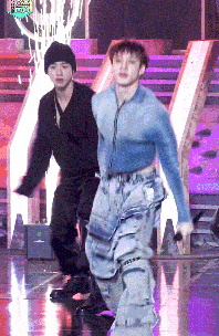 two men are dancing on a stage and one is wearing a blue sweater