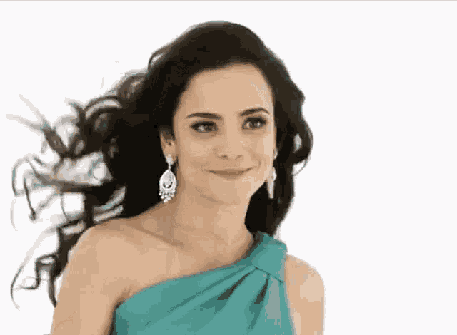 a woman in a blue one shoulder dress and earrings smiles