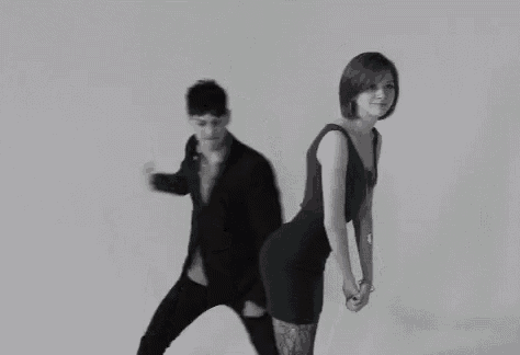 a man and a woman are dancing together in a black and white photo . the woman is wearing a black dress .
