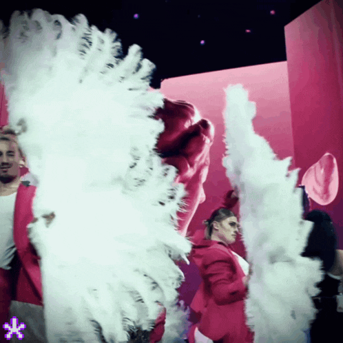 a man in a red jacket is standing in front of a pink wall